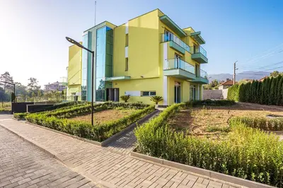 a yellow and blue building with a garden in front of it at Complex Europe in Dolna Banya