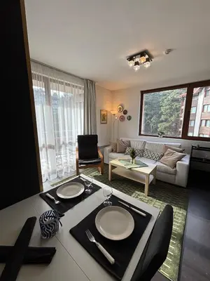 a living room with a table and a couch at Kosara Apartment Home2Host in Bansko