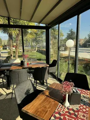 a dining room with a table and chairs and windows at Мотел КОМПЛЕКС GRILL and CHILL in Levunovo