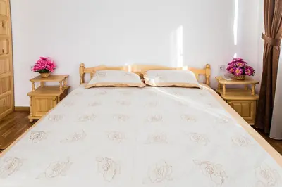 a bedroom with a white bed with two tables at Rodopsko Katche in Alamovtsi