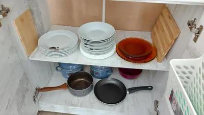 a shelf filled with plates and bowls and a pot at Аpartment C103 Grand Bansko 1 in Bansko