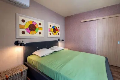 a bedroom with a green bed with two paintings on the wall at Plovdiv ArtNest - 1-Bedroom Cozy Apartments in Plovdiv