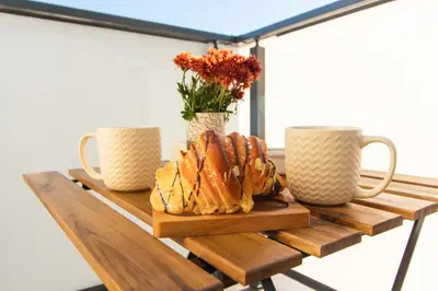 a wooden table with two mugs and a plate of pastries at Domus Apartments Vista in Plovdiv