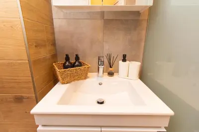 a white bathroom sink with a basket on it at Domus Apartments Vista in Plovdiv