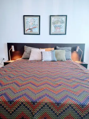 a large bed with a colorful blanket on it at Family Apartment Royal Tower in Bansko