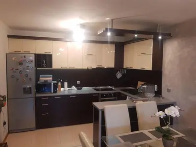 a kitchen with white cabinets and a table and a refrigerator at Apartment near Bulgaria Boulevard in Sofia