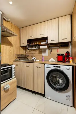 a washing machine in a kitchen with wooden cabinets at Convenient Studio with great view over Plovdiv in Plovdiv