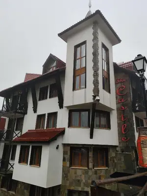 a large white building with a sign on it at Замъка in Pamporovo