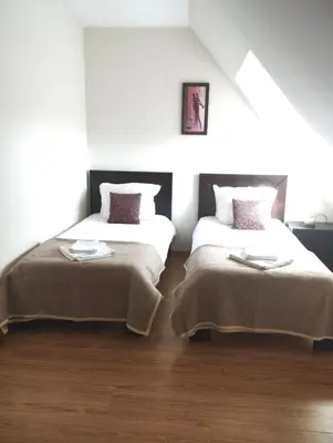 two beds in a room with white walls and wood floors at Dreaming apartment with tree Mountain view in Borovets