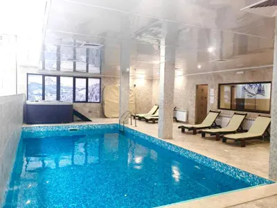 a swimming pool in a hotel room with chairs at Dreaming apartment with tree Mountain view in Borovets