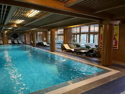 a swimming pool in a hotel with tables and chairs at PIRIN GOLF DELUXE PRIVATE STUDIO GABBY ground floor in Bansko