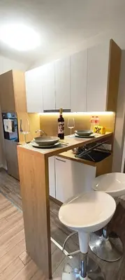 a kitchen with white cabinets and two bar stools at VB Residence Vitosha View Apartment in Sofia