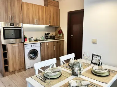 a kitchen with a dining room table with chairs and a kitchen with a sink at EMIS Alpine Retreat - Modern & Cozy & Bright in Bansko