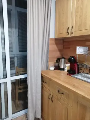 a kitchen with a counter and a window with a curtain at Апартамент Light blue in Troyan