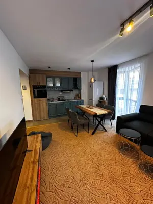 a living room with a table and a kitchen at Apartment 35 Mountain Lodge Pamporovo in Pamporovo