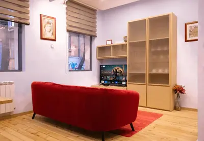 a living room with a red couch and a tv at Central 2BR Near Vitosha - Calm, Spacious Stay in Sofia