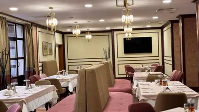 a restaurant with tables and chairs and a flat screen tv at Спа Хотел Орфей in Devin