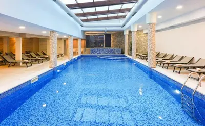 a large swimming pool with chairs in a building at Predela 2 Aparthotel Ski & Spa 200m from slopes in Bansko