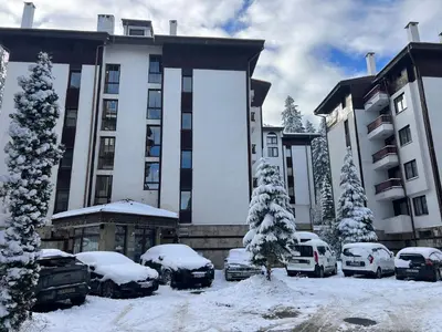a large building with cars parked in the snow at Elite Apartments Flora Residence in Borovets