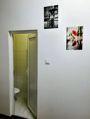 a bathroom with a toilet and two pictures on the wall at GuestHouse5 KARMA369 in Plovdiv
