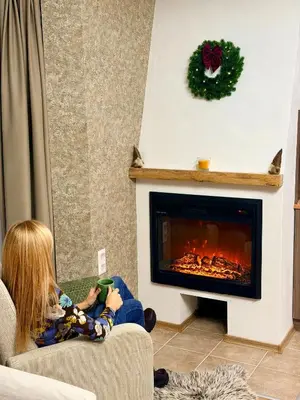 a woman sitting in a living room with a fireplace at Deluxe Apartment 34 Mountain Lodge Pamporovo in Pamporovo