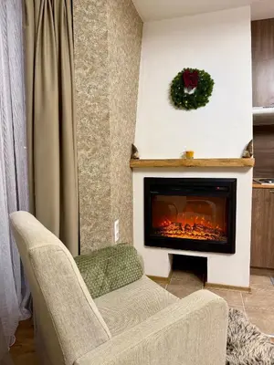 a living room with a fireplace and a chair at Deluxe Apartment 34 Mountain Lodge Pamporovo in Pamporovo