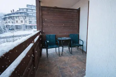 two chairs and a table on a balcony in the snow at Ametist - Comfort by the Gondola Lift in Bansko