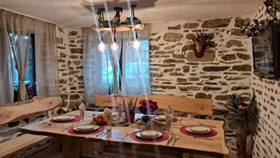 a dining room with a table and a stone wall at Rilski Chardak in Sapareva Banya