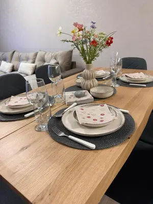 a wooden table with plates and glasses and a vase with flowers at Apart-Hotel Crow Bansko 3 in Bansko