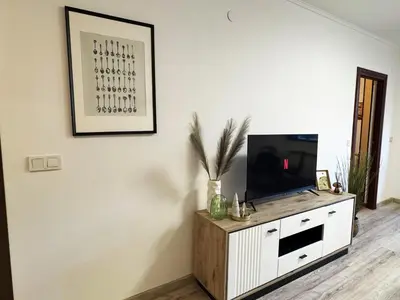 a living room with a tv on a white cabinet at Alpine Glow - Panoramic View near Gondola in Bansko