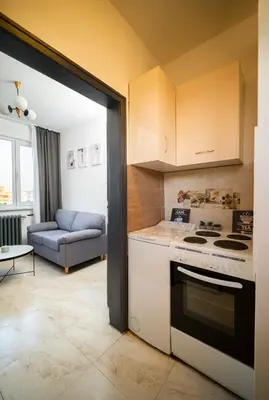 a kitchen with a stove top oven next to a couch at 2-Bedroom Apartment near Tokuda Hospital & Paradise Mall in Sofia