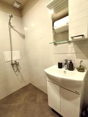 a white bathroom with a sink and a shower at Cozy 1BR Mountain View Suite for 4 Guests in Bansko