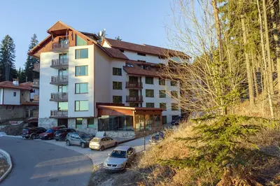 a building with cars parked in a parking lot at Апартамент Orpheus Forest in Pamporovo