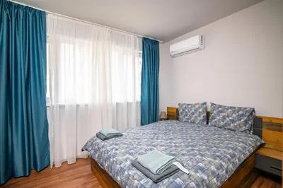 a bedroom with a bed and a window with blue curtains at Stylish 1 Bedroom Apartment - Quiet & Comfortable in Sofia