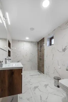 a white bathroom with a sink and a shower at Къща за гости Мартинели