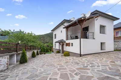 a house in the mountains with a stone patio at Къща за гости Мартинели