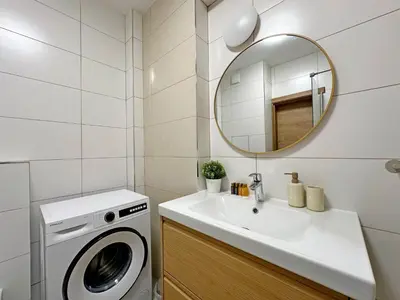 a bathroom with a washing machine and a sink at Spacious bright cozy 2BDR fast Wi-Fi next to Park in Sofia