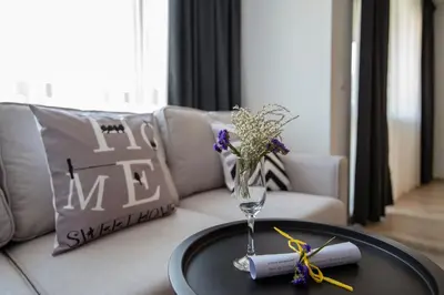 a vase with flowers on a table in front of a couch at Apartments by the river 2 in Plovdiv