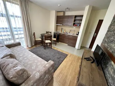 a living room with a couch and a table and a kitchen at Belmont urban one bedroom apartment in Bansko