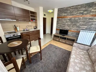 a kitchen and living room with a table and a couch at Belmont urban one bedroom apartment in Bansko