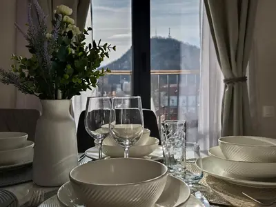 a table with plates and glasses and a vase with flowers at Plovdiv Hills Apartments with FREE Parking in Plovdiv