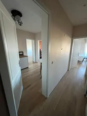 an empty living room with a white door and wooden floors at Lux, Spacious and Comfort Apartment next to National Palace of Culture in Sofia