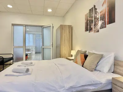 a bedroom with a large bed with white sheets at Top Centre 2BDR Apartment for 4 Guests next to Theater Tear and Laughter in Sofia