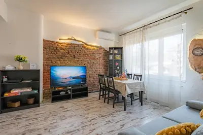 a living room with a brick wall and a table and a television at 1 min from NDK and Vitoshka street in Sofia