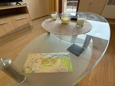 a glass table with two drinks and a book on it at Bansko Bliss - Peaceful Stay with Balcony Views in Bansko