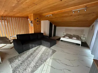 a living room with a black couch and a table at Къща за гости Алино Хаус in Alino