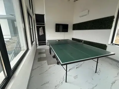 a green ping pong table in a room with windows at Къща за гости Алино Хаус in Alino