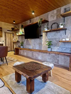 a living room with a tv on a stone wall at WoodLux in Pamporovo