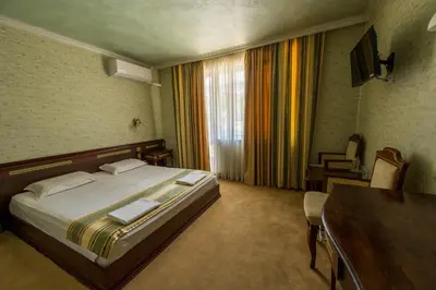 a hotel room with a bed and a desk and a window at Family Hotel Lazur in Kyustendil