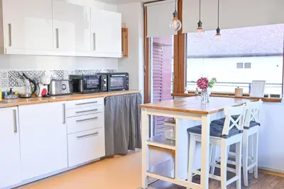 a kitchen with white cabinets and a wooden table at Comfortable 1-Bedroom Apartments in Bansko - Close to Gondola by Flat Mаnаger in Bansko